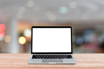 Wall Mural - Laptop computer with blank screen on wood table over blur shopping mall background. Mock up, template for your design.