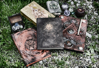 Grunge still life with witch book of magic spells on the grass in the garden.