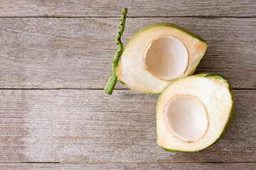 Wall Mural - green coconut cut in half sliced isolated on wooden table background.