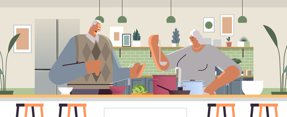 Wall Mural - happy senior couple preparing healthy food at home grandparents cooking together old age concept