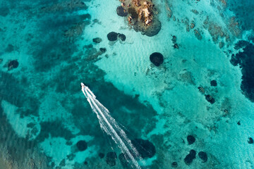 Wall Mural - View from above, stunning aerial view of a boat sailing on a crystal clear, turquoise water. Giardinelli island, La Maddalena Archipelago, Sardinia, Italy.