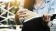 © Phushutter - Close up hands of woman reading a book at park outdoor.