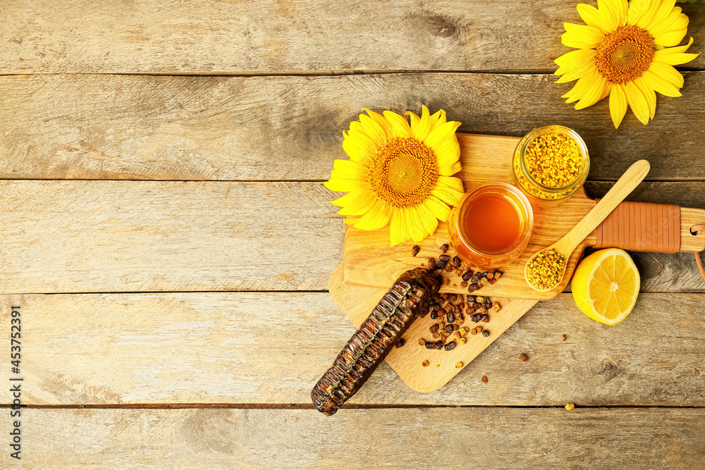 Different bee products with lemon on wooden background
