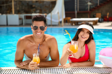 Poster - Young couple with cocktails in swimming pool