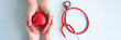 Child and mother holding red toy heart on background of stethoscope closeup