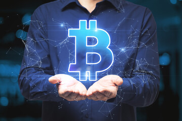 Wall Mural - Businessman hand holding creative polygonal bitcoin hologram on blurry background. Cryptocurrency and finance concept.