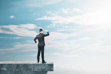 Poster - Businessman on abstract concrete edge looking into the distance on creative bright sky background with mock up place. Future, tomorrow and success concept.