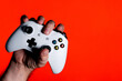 A photo of a man hand clutching a white gamepad on a bright red background with a place for the advertised text