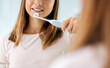 © Syda Productions - dental care, hygiene and people concept - happy smiling teenage girl with electric toothbrush brushing teeth at bathroom