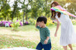 © amorn - Happy cheerful Asian little boy running and playing with kite flying with mother outdoor in the park. Little boy and mother having fun, enjoy, relaxing with kite flying together. Family, kid, playing