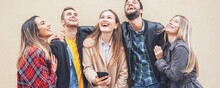 Group Of Friends Standing By The Wall Background And Enjoying Each Other-  Teenagers Using Smartphone And Smiling While Trying To Take A Selfie- Technology Concept