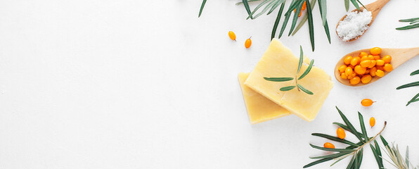 Handmade natural herbal sea buckthorn soap with ingredients on a white background. Top view, copy space. Banner