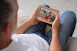 © New Africa - Senior man holding frame with photo of couple at home, closeup