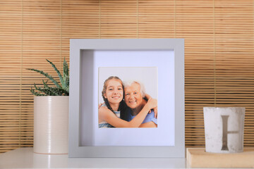 Sticker - Frame with photo of elderly woman and her granddaughter on white table indoors