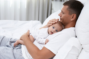 Poster - Happy father holding his cute baby on bed at home