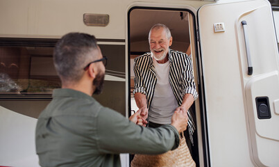 Wall Mural - Mature man with senior father unpacking by car outdoors, caravan holiday trip.