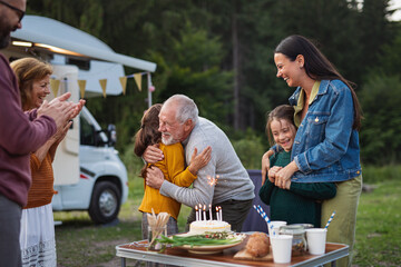 Wall Mural - Multi-generation family celebrating birthday outdoors at campsite, caravan holiday trip.