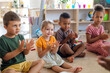 © Halfpoint - Group of small nursery school children sitting on floor indoors in classroom, clapping.