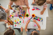 © Halfpoint - Top view of group of small nursery school children with teacher indoors in classroom, painting.