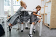 © zzzdim - Little schoolgirls sitting on the desk, having fun. One is writing and giggling