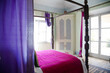 Four poster bed with purple bedding in bedroom