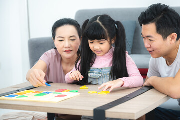 Asian children family with father and mother at home, little girl childhood development education concept, happy young cute daughter having fun to learning with eltern family at home