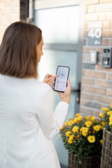 Wall Mural - Female closes the door or turns on the house alarm with phone