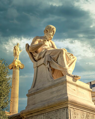 Plato, the ancient Greek philosopher and Apollo god marble statues under dramatic cloudy sky