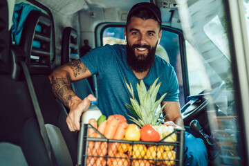 Wall Mural - Young bearded man is driving delivery van. He is working in everyday or daily home delivery service.