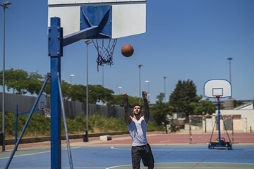 Sticker - Young sporty guy on the outdoor basketball court throwing the ball to the hoop