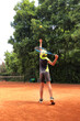 © Anna - Boy is about to execute tennis serve on outdoor tennis court during  training, active lifestyle concept.
