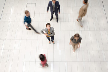 Canvas Print - Businesswoman standing in busy office hallway