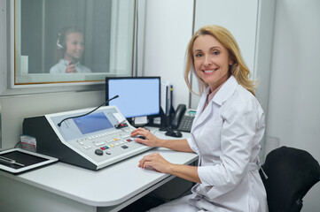 Joyous middle-aged doctor performing an audiometry test