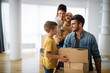 © NDABCREATIVITY - Happy family with children moving with boxes in a new apartment house.