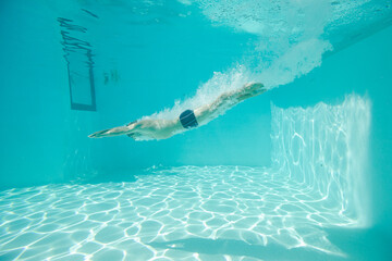 Man swimming underwater in pool