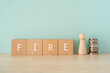 © ELUTAS - 早期リタイア、FIRE｜「FIRE」と書かれた積み木と人形とお金