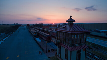 Wall Mural - Sunrise With Blue, Red Sky and Clouds Looking Over a Train Station and Yard