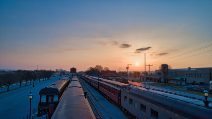 Wall Mural - Sunrise With Blue, Red Sky and Clouds Looking Over a Train Station and Yard