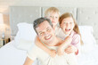 © KOTO - Father and children hugging in bedroom