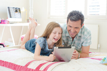 Wall Mural - Father and daughter using digital tablet on bed