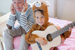 Father covers his ears when son playing guitar