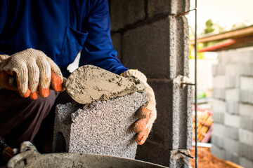 Close-up of a professional worker using a pan knife to build a brick wall with cement bricks and cement. Business ideas and the construction industry