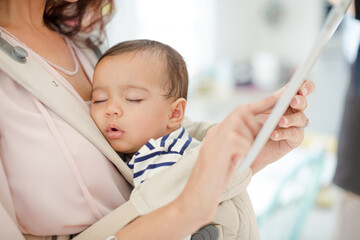 Mother with sleeping baby girl using digital tablet