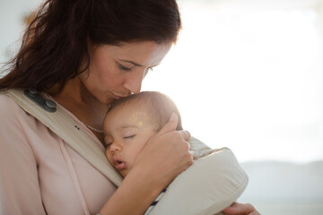 mother kissing sleeping baby girl