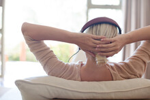 Woman Listening To Headphones On Sofa