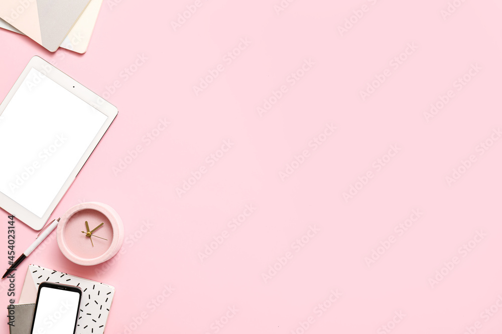 Alarm clock with office supplies, tablet computer and mobile phone on color background