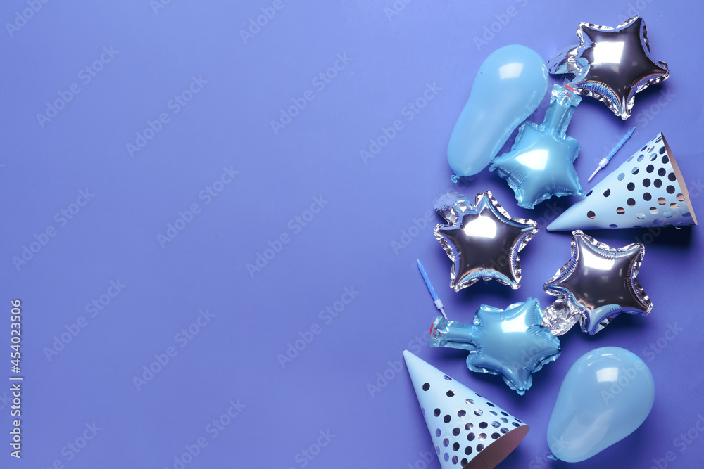 Party hats, balloons and candles on color background