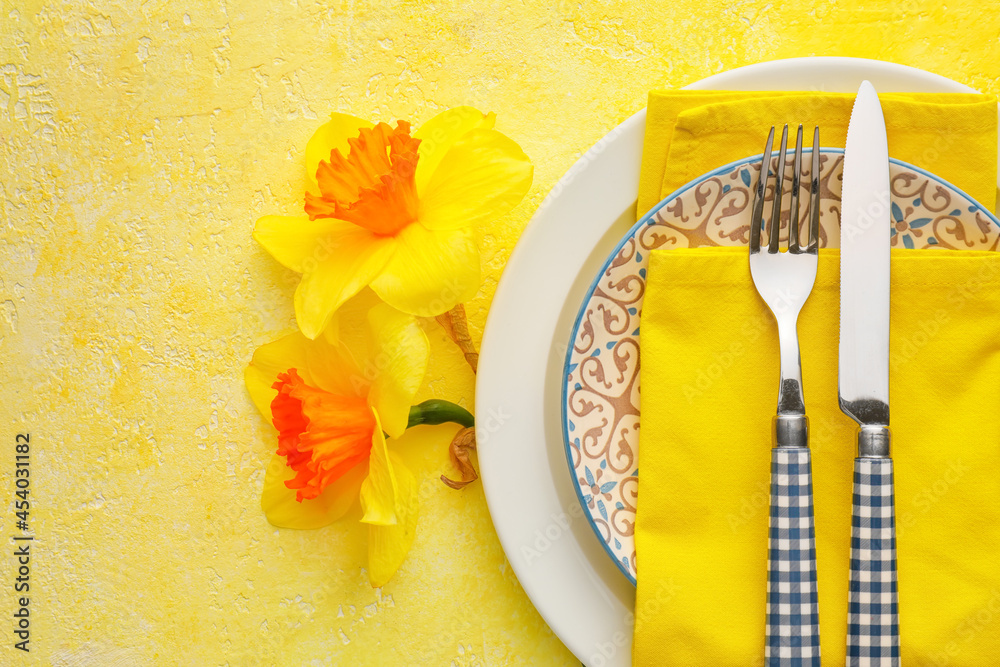 Beautiful table setting with narcissus flowers on color background