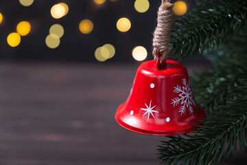 Wall Mural - Christmas composition with red bell on fir tree on background garland lights.