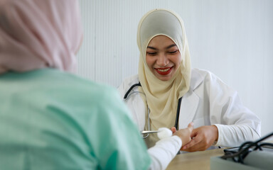 Wall Mural - Young female muslim doctor cleaning patient's wrist using cotton swap with alcohol and preparing for a vaccine shot